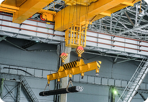 Yellow overhead crane carries cargo in engineering plant shop