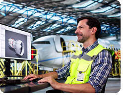 man working on computer with airplane in hanger
